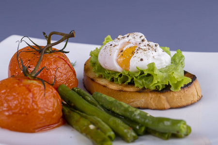 把鸡蛋放在一块面包上, 用油炸青豆西红柿和芝麻菜放在盘子上, 合上