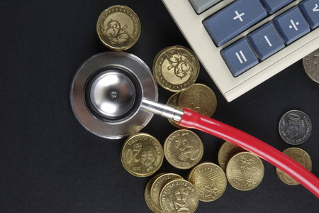 红色的听诊器和黑色背景上的硬币。医疗