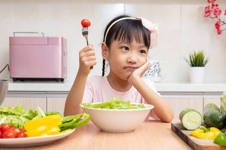 亚洲华人小女孩在厨房吃沙拉在家里