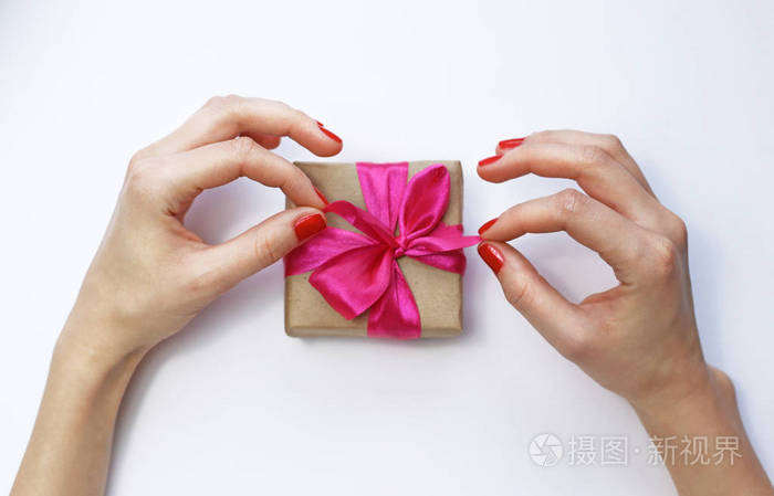 要打开一个礼物.在白色背景上的女性手