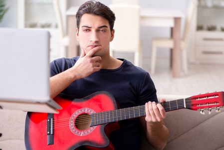 年轻人在家里练习弹吉他图片