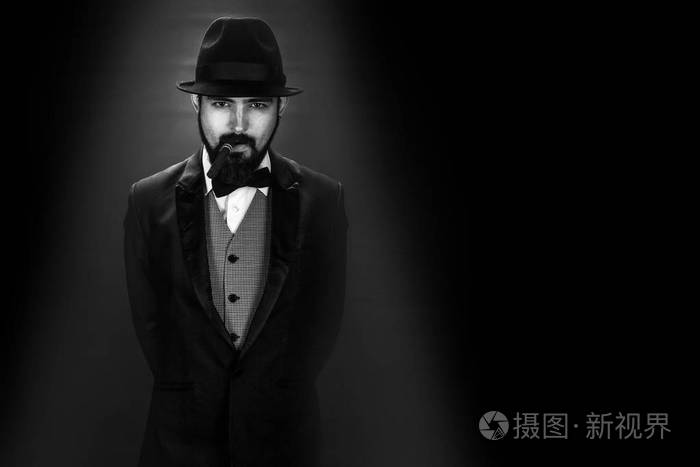 黑色和白色的胡子吸烟绅士的肖像与蝴蝶和黑帽子西装