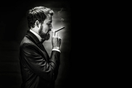男子吸烟雪茄黑色和白色的胡子吸烟的雪茄绅士在西装的肖像照片
