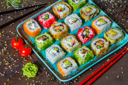 不同的寿司食物种类送达黑色背景。美味的新鲜寿司卷与鱼和米饭在板上的特写。在一家餐厅的木盘子寿司卷送达