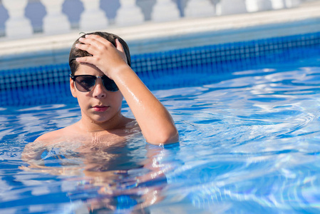 年幼的孩子在海边的游泳池边上, 用手压着头, 惊呆了, 脸上带着羞愧和