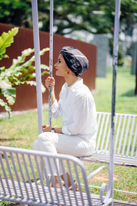一个年轻的穆斯林妇女戴头巾 头巾, 头巾 的肖像。她坐在秋千上