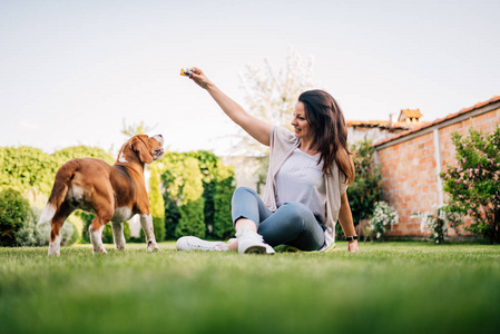 可爱的年轻女子玩她的猎犬狗在后院