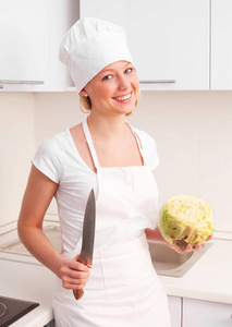 漂亮的年轻女子在厨房里切白菜