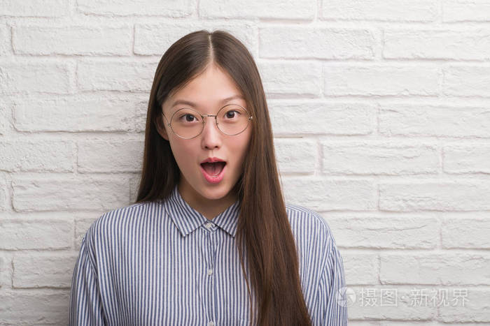 年轻的中国商界妇女在砖墙上吓了一惊, 惊恐万分, 惊恐不已.