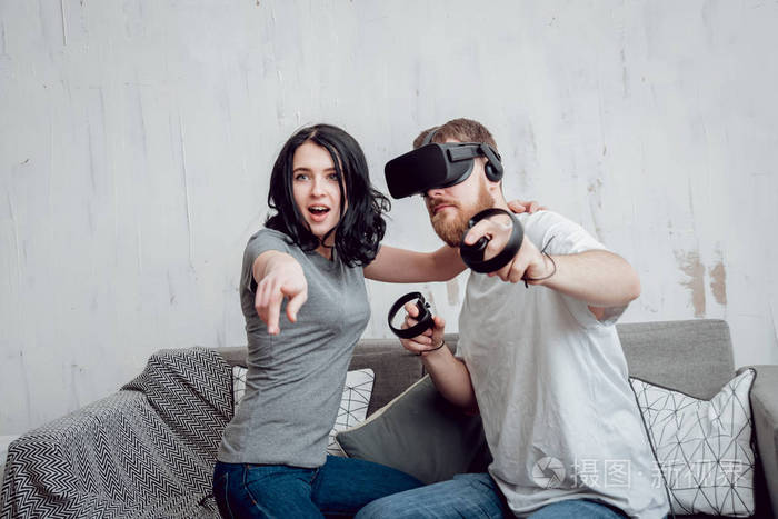 年轻男子与女朋友玩游戏与虚拟现实护目镜在家里。Vr 技术