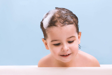 可爱的婴儿宝宝的肖像洗澡泡沫泡沫.小孩子在浴缸里往下看.