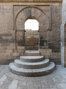 木制的老年人拱形扇敞开的门，三个步骤和石墙