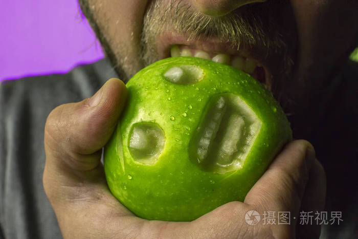 一个人咬着一个绿色的苹果, 嘴里含着痛苦的叫声.