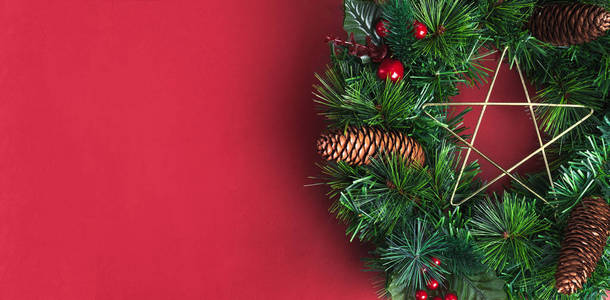 绿松圣诞花圈与星和松树锥体, 樱桃装饰项目在红色墙壁背景. 复制用于添加文本或设计的空间。庆典节日 greeing 贺卡