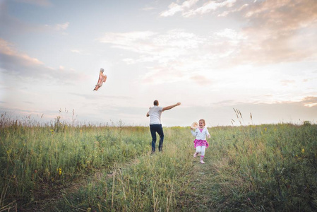 愉快的家庭爸爸和孩子跑在草甸与风筝在夏天对自然. 复古风格