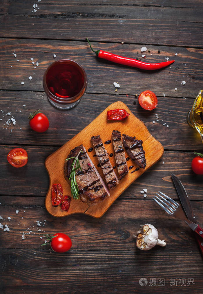 烤的牛肉用香料调味牛排上木板与新鲜的樱桃番茄和红辣椒