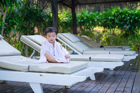 亚洲男孩用白色毛巾上的甲板躺椅或太阳休息