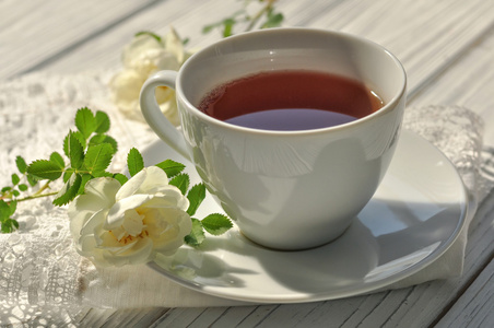 白花茶一杯茶,花边餐巾和精致的白花,白色的木制表面上摄影图