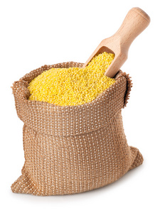 用勺在白色背景上孤立的麻袋里的小米照片