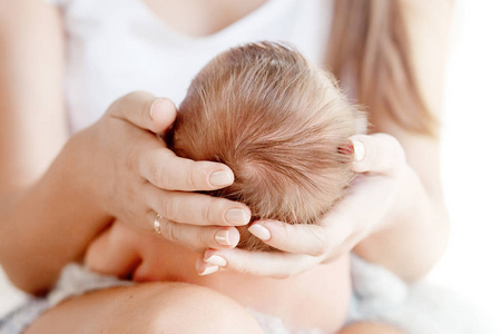 母亲手捧着初生婴儿的头。孩子手里拿着妈妈。爱的母亲手抱着可爱的新生儿婴儿