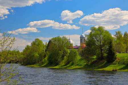 春天的风景与教会在一条深, 快速的河的银行