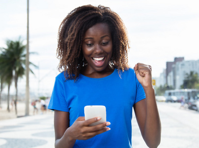 在一件蓝色的衬衫与电话欢呼非洲女人