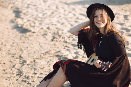 幸福的年轻女人在夏威夷四弦琴在海滩上玩