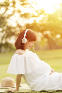 怀孕妇女放松和听音乐与耳机图片