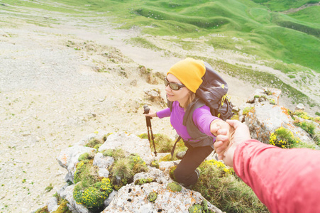 登山者帮助一个年轻的登山女子到达山顶。一个男人伸出援手给女人。从上面查看