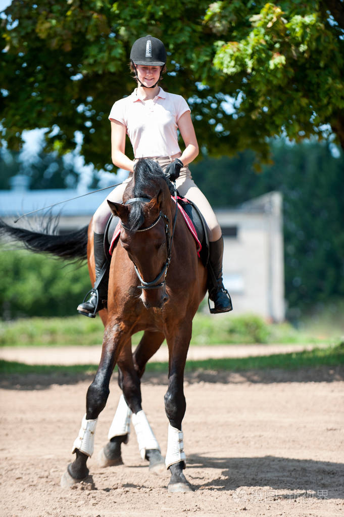 少年女孩骑马骑马在竞技场上运动训练课.动感多彩的户外垂直图像