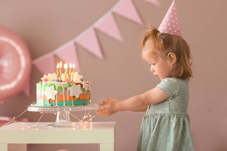 可爱的小女孩与美味的蛋糕在房间装饰为生日聚会