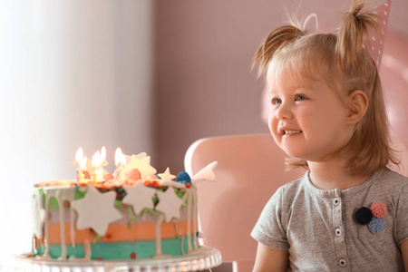 可爱的小女孩与生日蛋糕坐在椅子在房间里