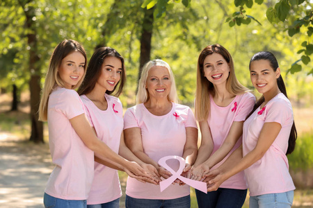 美丽的不同年龄的妇女持有粉红色丝带户外。乳癌概念