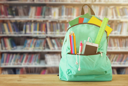 书包前有文具和笔记本, 书架上有书, 图书馆。返回学校概念