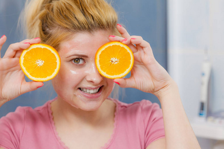 妇人抱着橙色的脸上有凝胶面膜