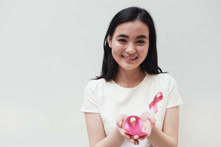 亚洲年轻女子持有粉红色丝带, 乳腺癌意识和10月粉红色概念