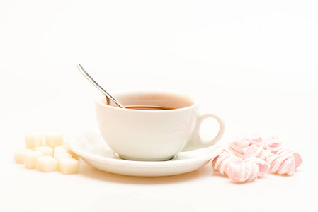 杯子里有红茶和糖果。茶歇概念。作为甜点准备的饮料和糖果。杯中充满黑色酿造茶, 勺子和棉花糖堆和精制糖的白色背景