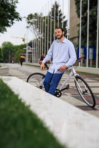 年轻的时髦人与固定齿轮自行车在城市的街道上