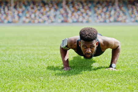 非裔美国男运动员在运动衫做俯卧撑运动在体育场