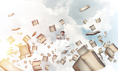 年轻的小男孩保持眼睛闭着, 看着集中, 而在空中飞行书籍与多云影像的背景下沉思