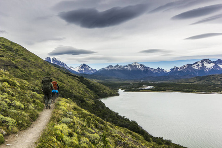 两名男子徒步旅行在巴塔哥尼亚山脉上，托雷斯德尔潘恩与灰色的天空