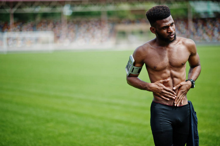 非洲裔美国男性运动员运动裸躯干男子与运行的运动手臂的手机, 摆在足球场绿草