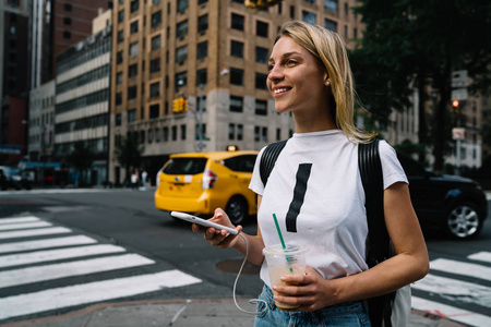欢快的年轻女性游客走在城市街道路过的汽车和人行横道享受大城市, 微笑的时髦女孩兴奋与快速出租车服务呼叫驾驶室通过应用 smart