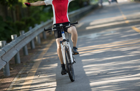 骑自行车的妇女骑车与伸展的武器在道路上