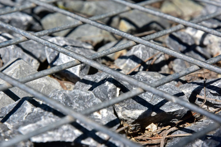 电线格宾石栅栏。金属笼充满岩石。带笼式围岩围栏的织构背景