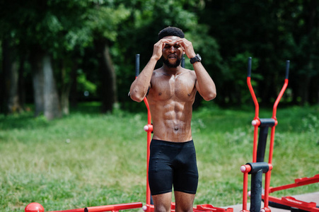 非洲裔美国男性运动员运动裸躯干男子与运行的运动手臂的情况下, 在街头锻炼模拟器做练习