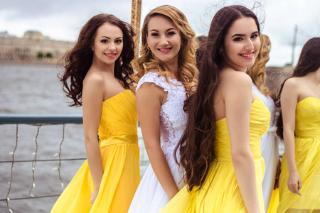 美丽的新娘和黄色相似的连衣裙上一个夏天在一起的两个伴娘露台海上餐厅