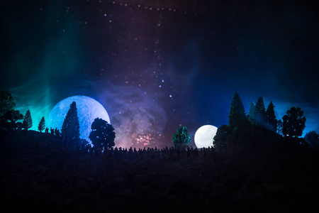 一大群人在夜里在森林里看着大满月的身影。装饰的背景与夜空的星星, 月亮和空间元素。选择性对焦。超现实世界