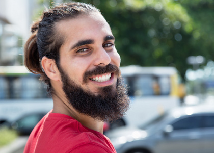 快乐的阿拉伯人与城市的胡子和红色衬衫