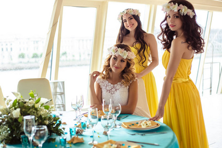 美丽的新娘和两个伴娘穿着黄色类似一起在海上餐厅